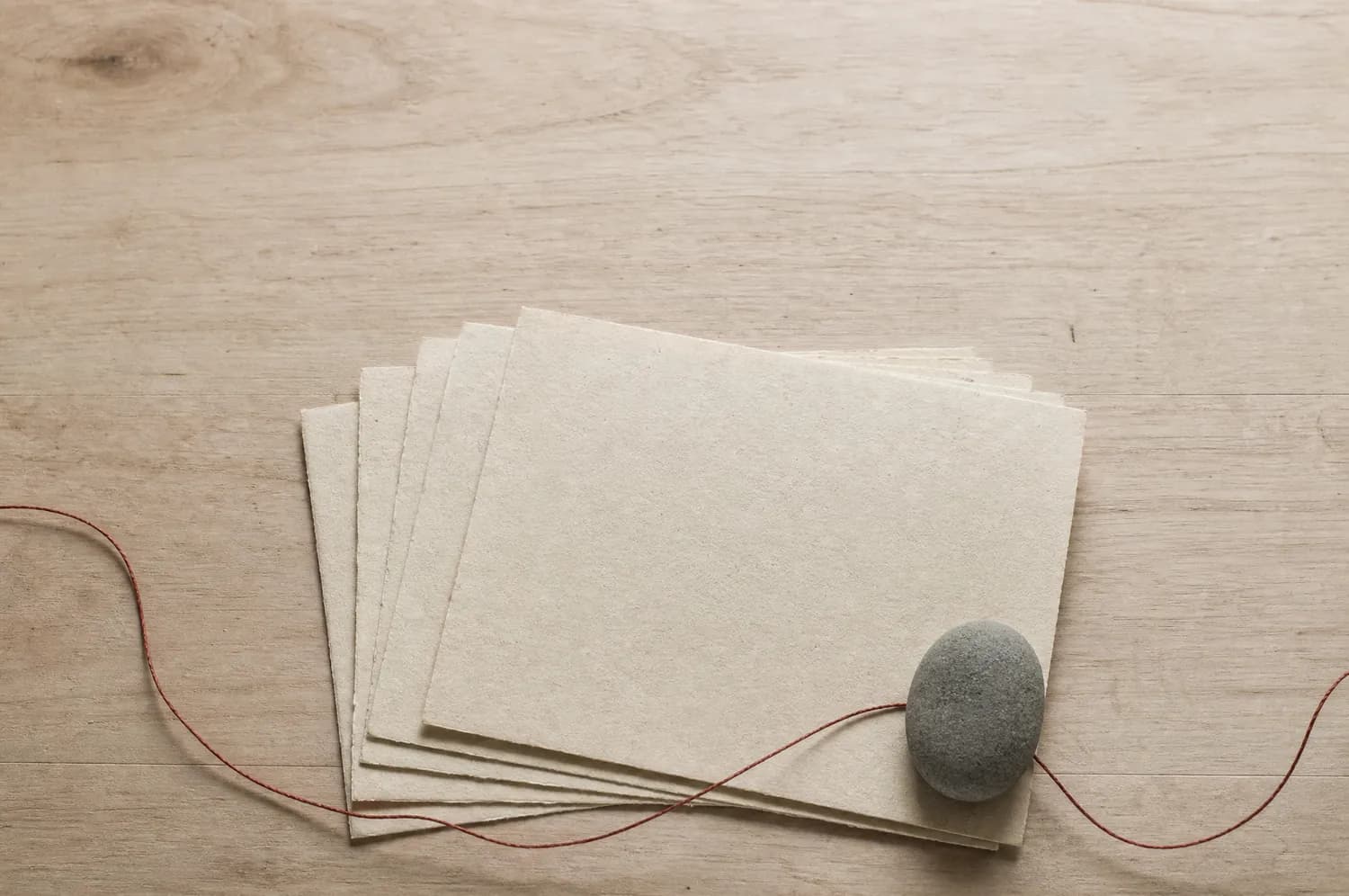 A fanned stack of blank warm paper sheets on a wooden surface.